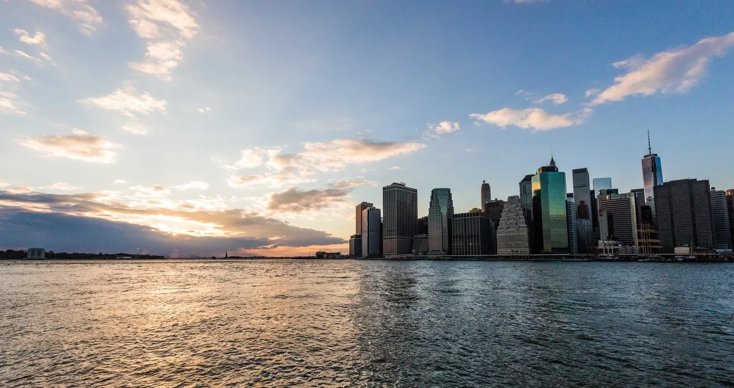 Lower Manhattan seen across the harbor at sunset.